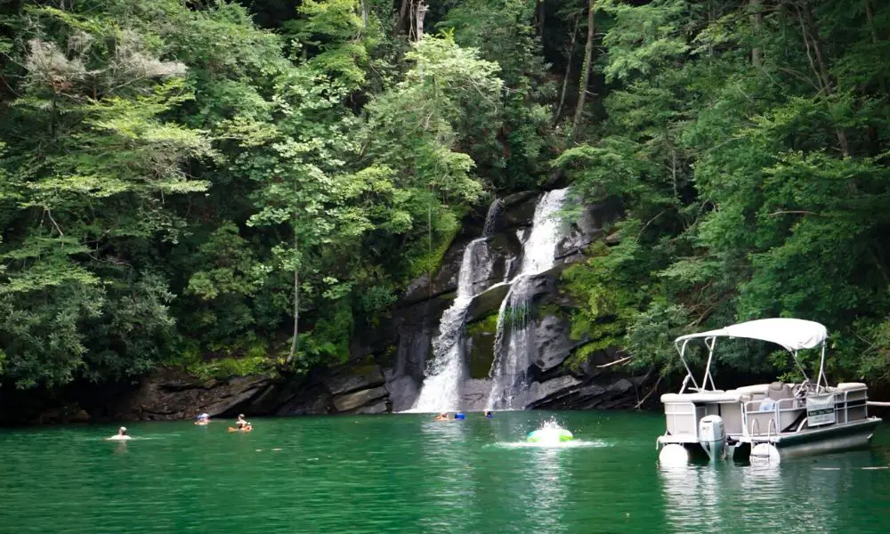 pontoon boat on lake jocassee and people swimming by the waterfall